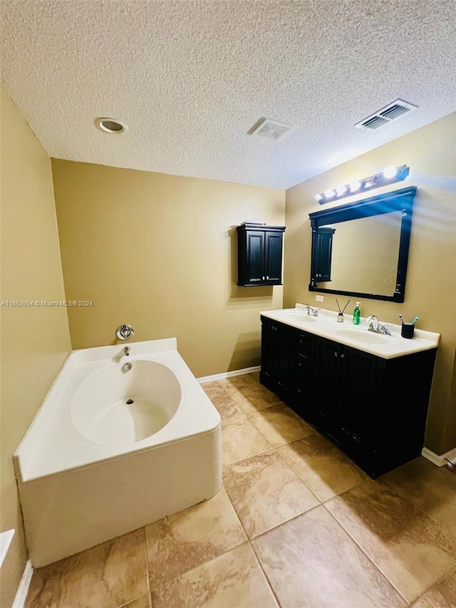 bathroom with vanity, a textured ceiling, tile patterned flooring, and a washtub