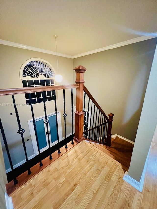 stairway with ornamental molding and hardwood / wood-style flooring