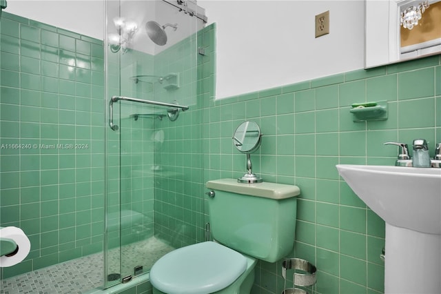 bathroom featuring tile walls, sink, an enclosed shower, and toilet