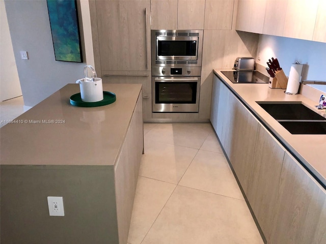 kitchen featuring stainless steel appliances, light tile patterned floors, and sink