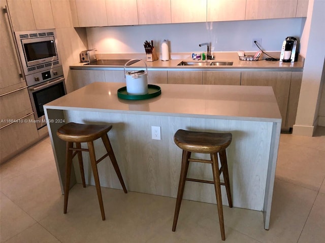 kitchen featuring a kitchen breakfast bar, stainless steel appliances, a center island, and sink