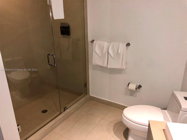 bathroom featuring tile patterned flooring, a shower with door, toilet, and vanity