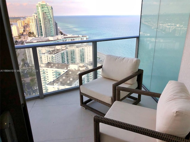 balcony at dusk featuring a water view