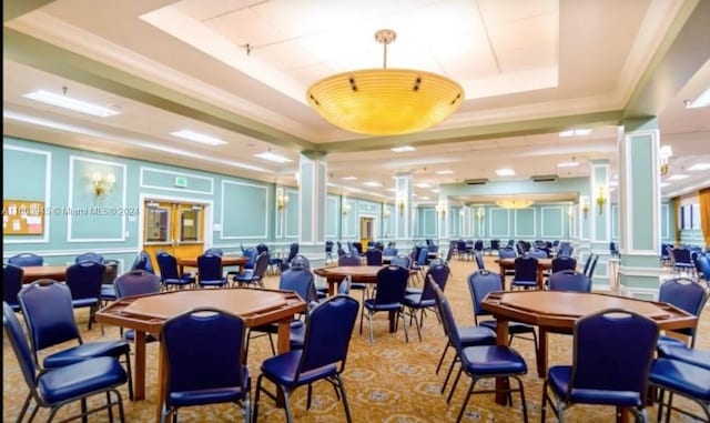 dining space featuring carpet floors, a tray ceiling, crown molding, and decorative columns