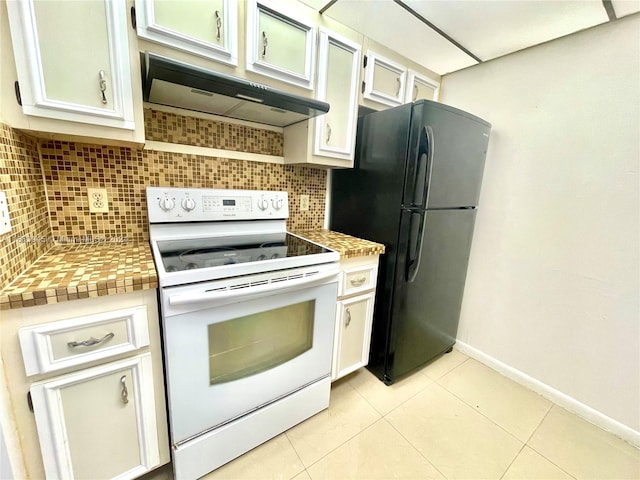 kitchen featuring tasteful backsplash, white cabinetry, light tile patterned floors, black refrigerator, and white range with electric cooktop