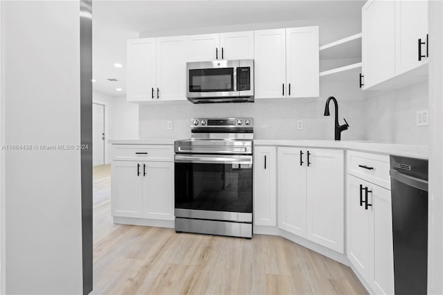 kitchen featuring appliances with stainless steel finishes, light wood-type flooring, backsplash, and white cabinetry