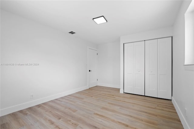 unfurnished bedroom with light wood-type flooring and a closet