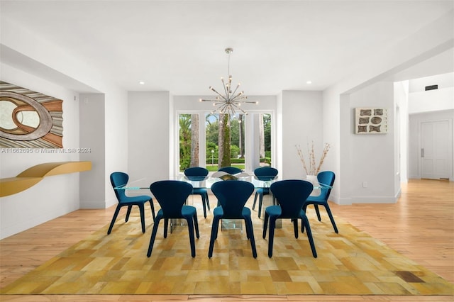 dining area with light hardwood / wood-style flooring and a chandelier