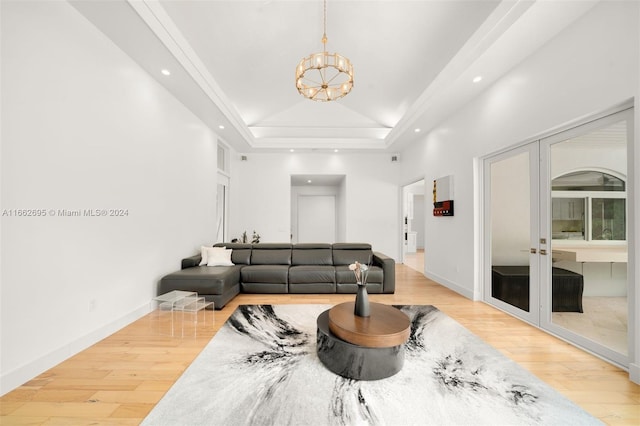 living room with light wood-type flooring, a raised ceiling, and an inviting chandelier