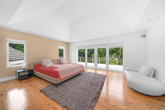 bedroom featuring access to outside, lofted ceiling, french doors, and light hardwood / wood-style flooring