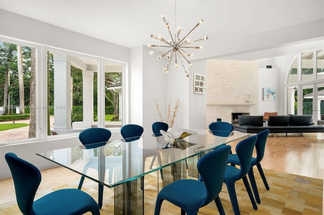 dining room with a fireplace, a chandelier, and light wood-type flooring