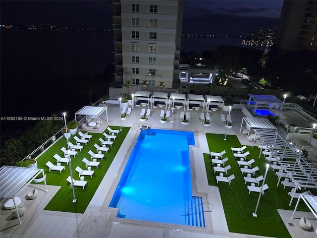 pool at night featuring a patio area