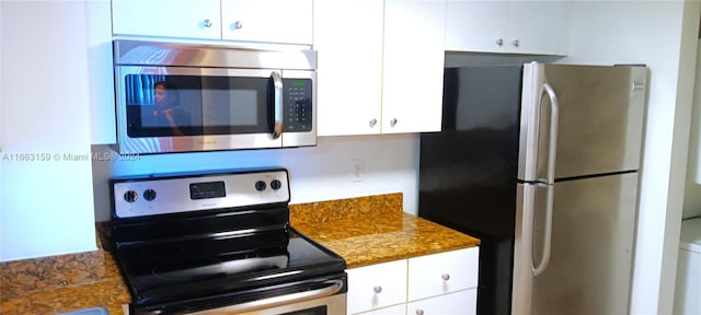 kitchen featuring stainless steel appliances, white cabinetry, and dark stone countertops