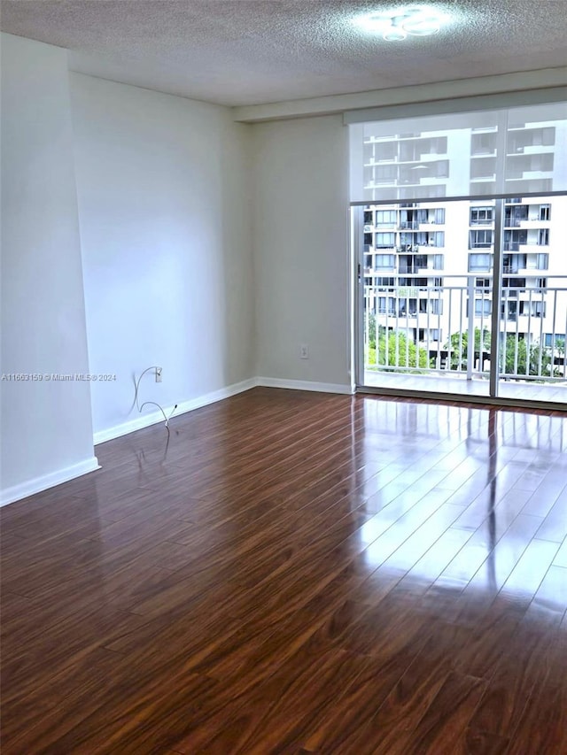 empty room featuring a textured ceiling and dark hardwood / wood-style flooring