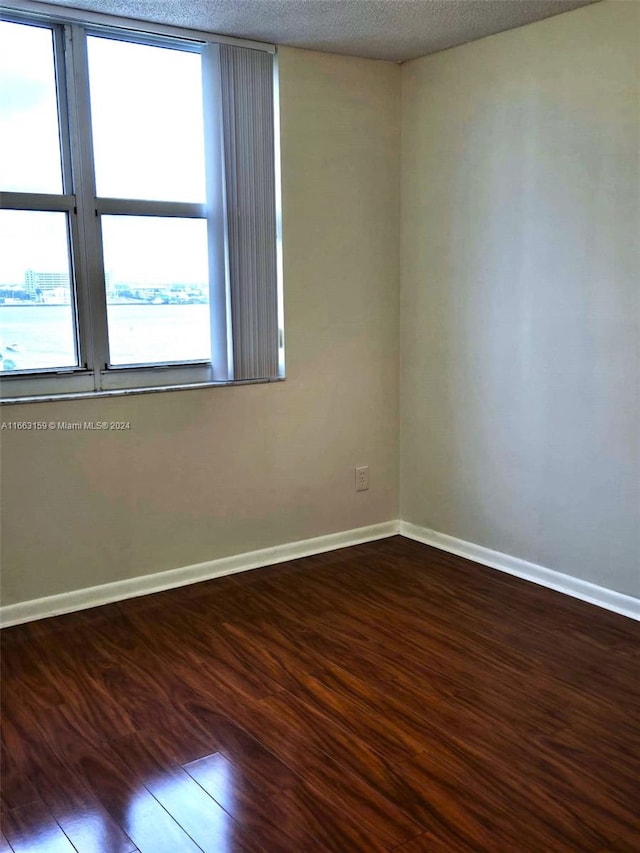 unfurnished room with wood-type flooring and a textured ceiling