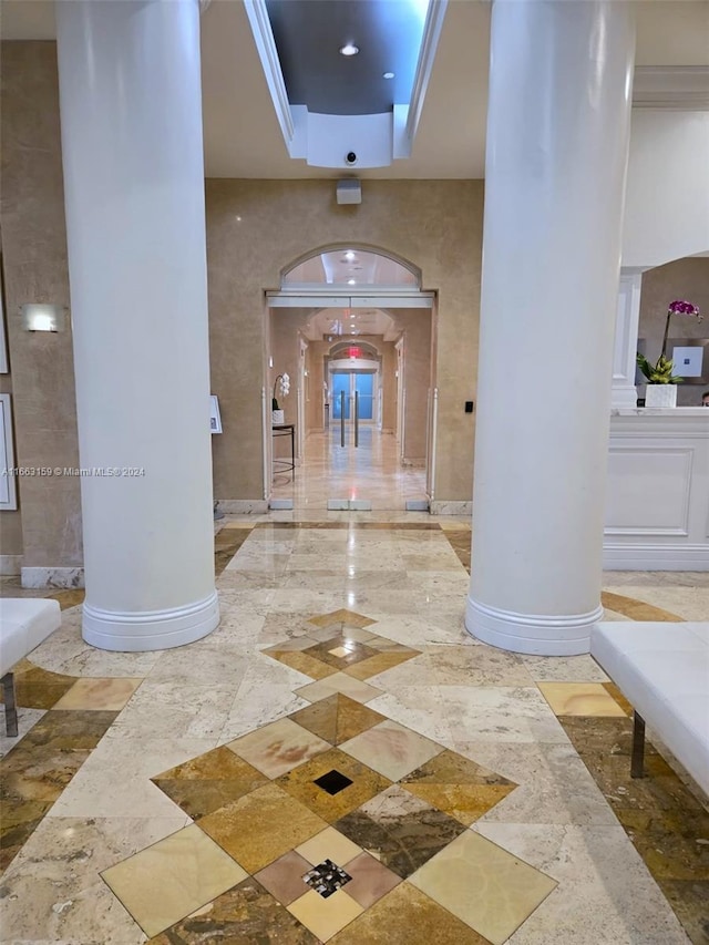 corridor featuring a tray ceiling and decorative columns