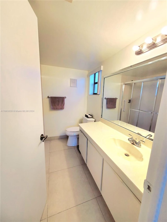 bathroom with tile patterned flooring, an enclosed shower, vanity, and toilet