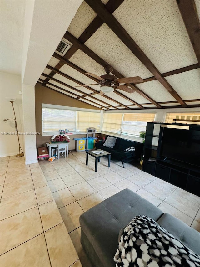 living room featuring lofted ceiling with beams, light tile patterned flooring, ceiling fan, and a wealth of natural light