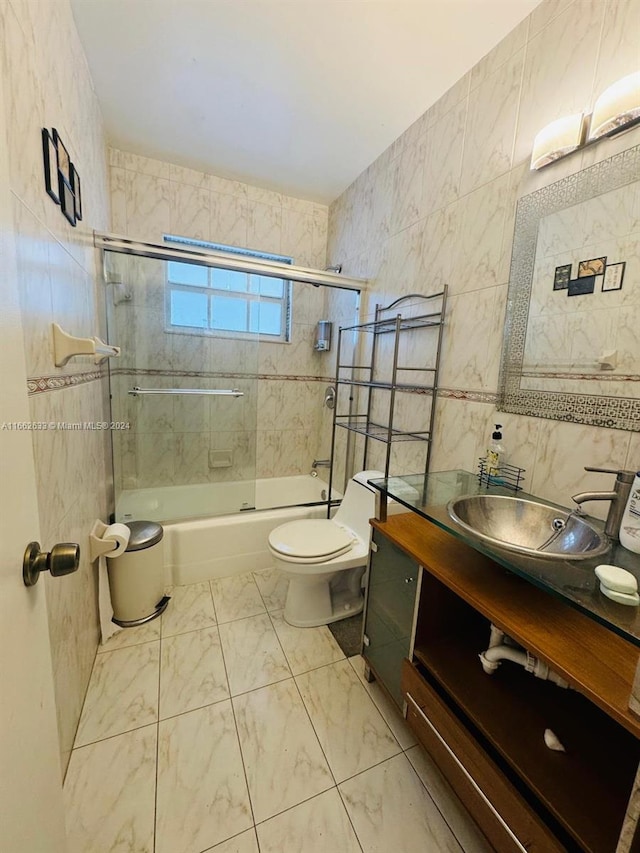 full bathroom featuring vanity, toilet, tile walls, and combined bath / shower with glass door