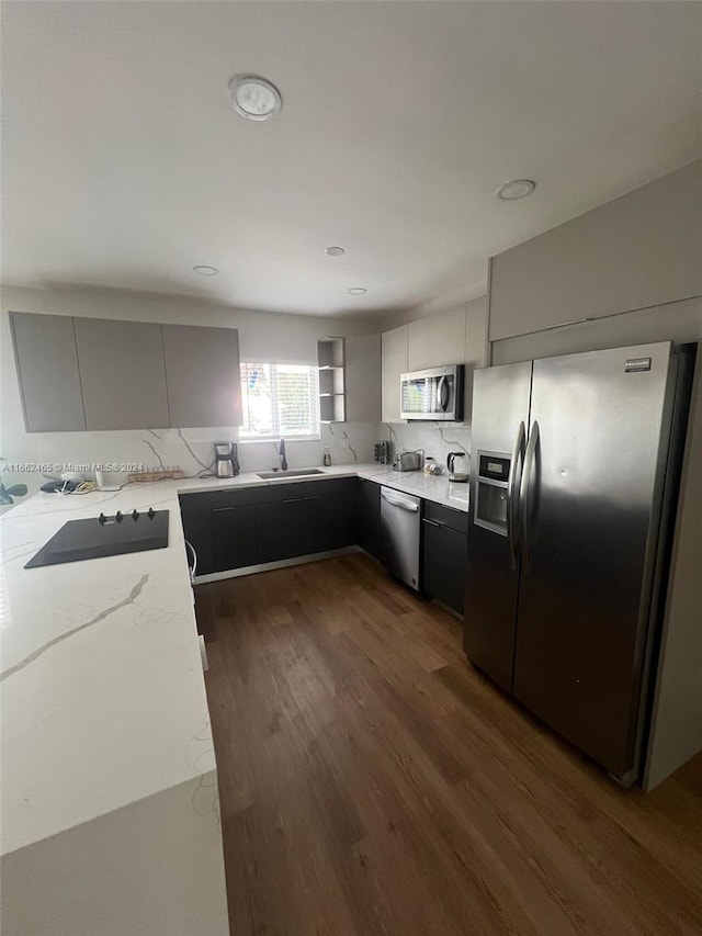 kitchen with light stone counters, dark wood-type flooring, sink, gray cabinetry, and appliances with stainless steel finishes