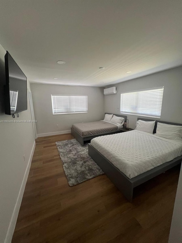 bedroom with dark wood-type flooring and an AC wall unit