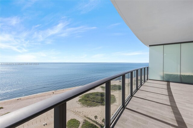 balcony featuring a view of the beach and a water view