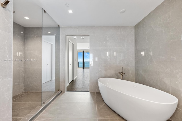 bathroom with shower with separate bathtub, tile walls, and tile patterned floors