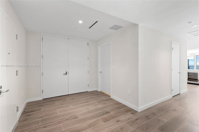 unfurnished room with light wood-type flooring and wine cooler