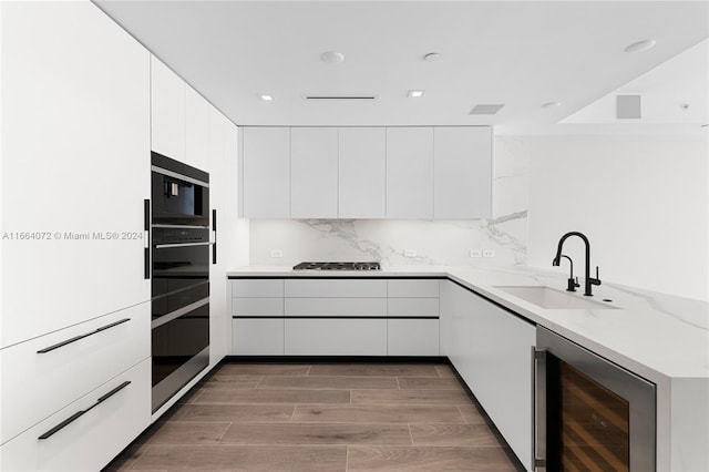 kitchen with hardwood / wood-style flooring, sink, white cabinets, beverage cooler, and light stone countertops