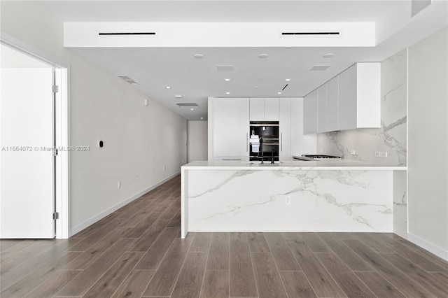 kitchen featuring light stone countertops, white cabinets, light hardwood / wood-style floors, and double oven