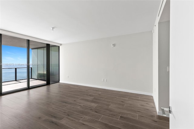 empty room featuring a water view, a wall of windows, and dark hardwood / wood-style flooring