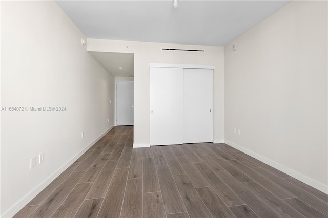 unfurnished bedroom with a closet and dark hardwood / wood-style flooring