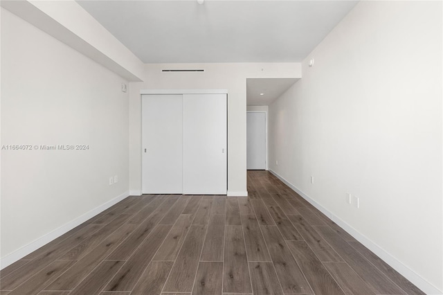 unfurnished bedroom with a closet and dark hardwood / wood-style flooring