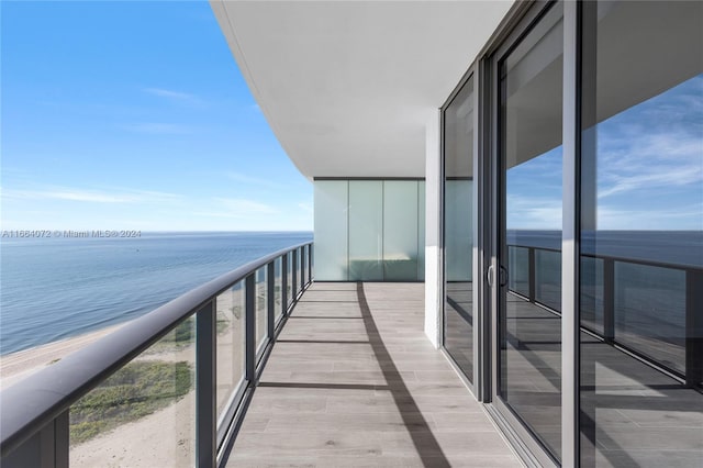 balcony featuring a view of the beach and a water view