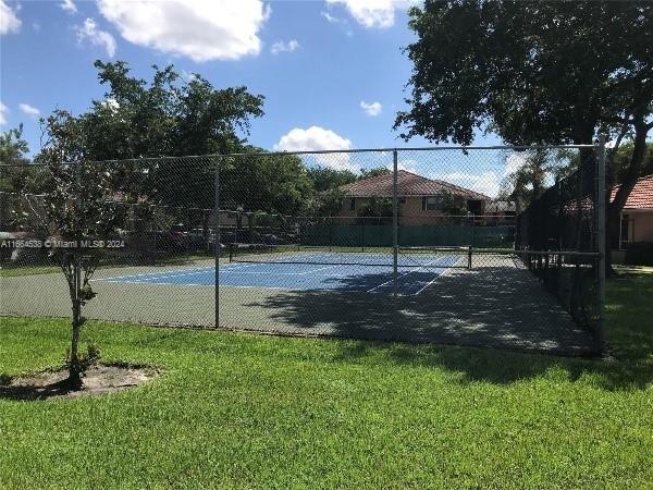 view of tennis court featuring a yard