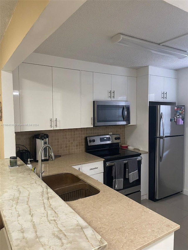 kitchen with white cabinets, backsplash, appliances with stainless steel finishes, and sink