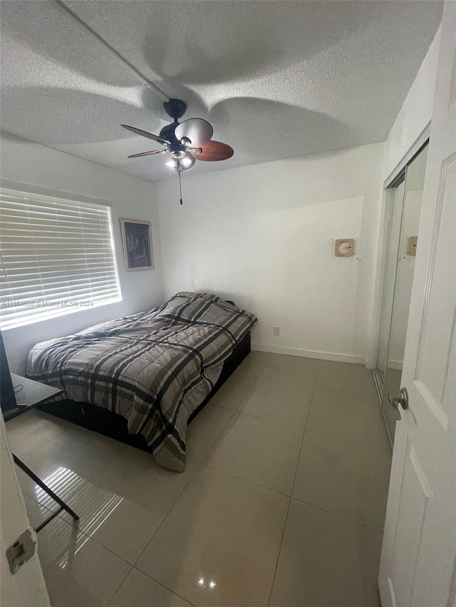 bedroom with a textured ceiling, tile patterned flooring, and ceiling fan