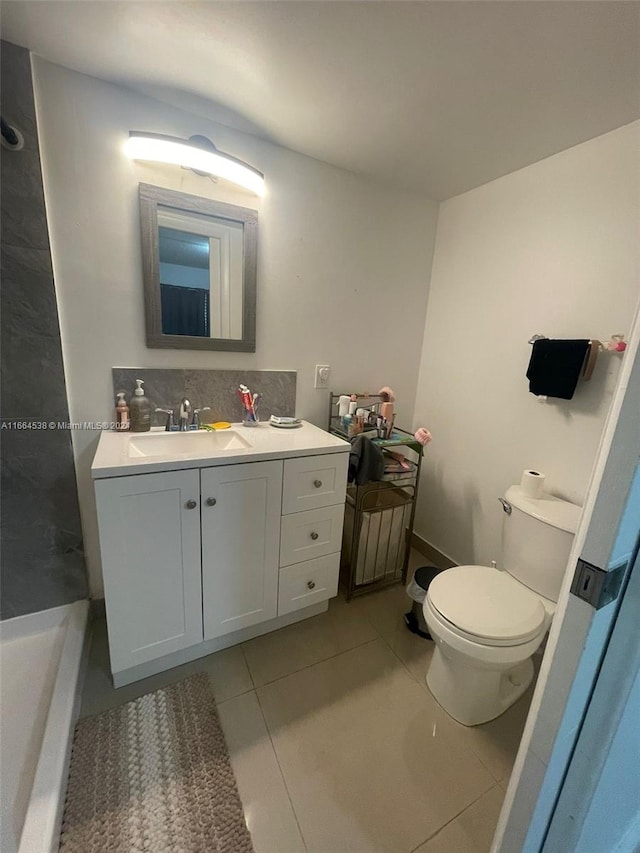 bathroom with backsplash, vanity, a tub, toilet, and tile patterned floors