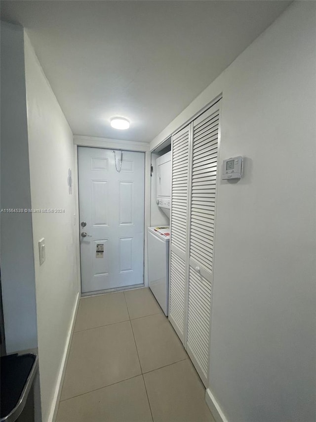 corridor with stacked washer / drying machine and light tile patterned flooring