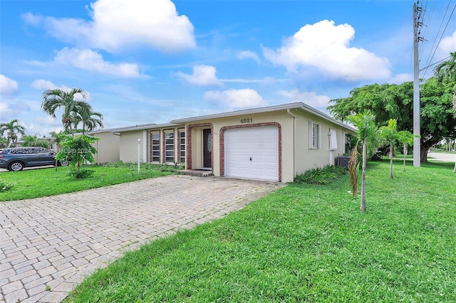 ranch-style house featuring a garage, a front lawn, and central AC