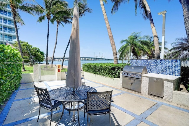 view of patio / terrace featuring an outdoor kitchen, a water view, and a grill