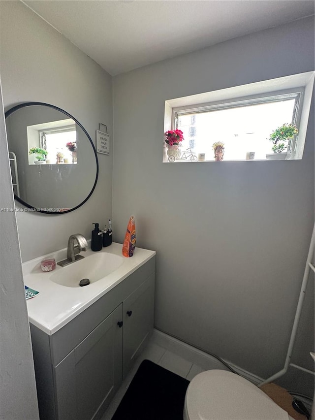 bathroom with a healthy amount of sunlight, tile patterned flooring, vanity, and toilet