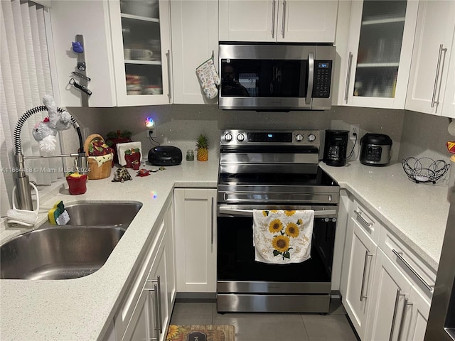 kitchen featuring light stone counters, sink, stainless steel appliances, and white cabinets