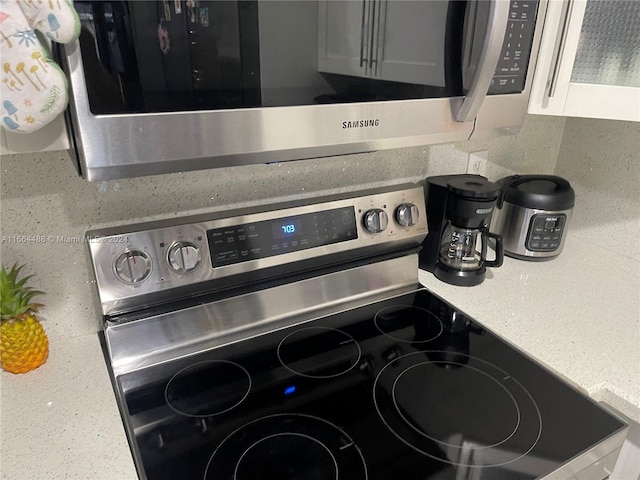 details with appliances with stainless steel finishes, tasteful backsplash, and white cabinetry