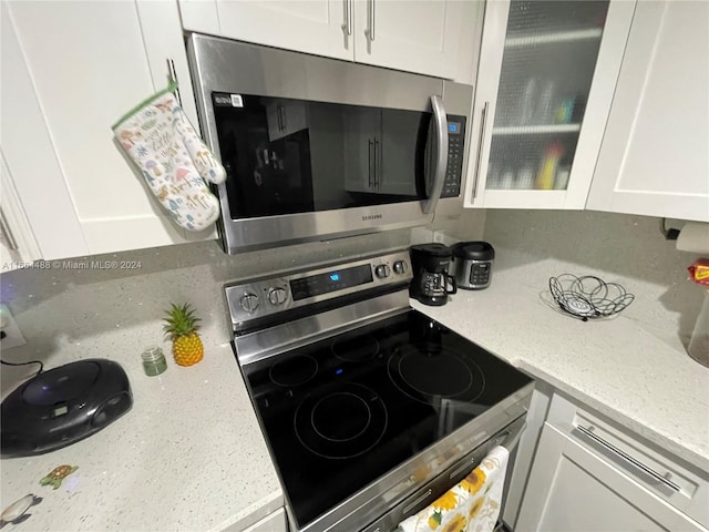 kitchen featuring appliances with stainless steel finishes, light stone counters, and white cabinets