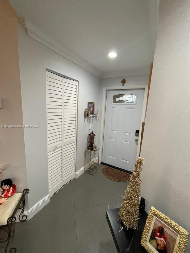 doorway to outside featuring dark tile patterned flooring and crown molding