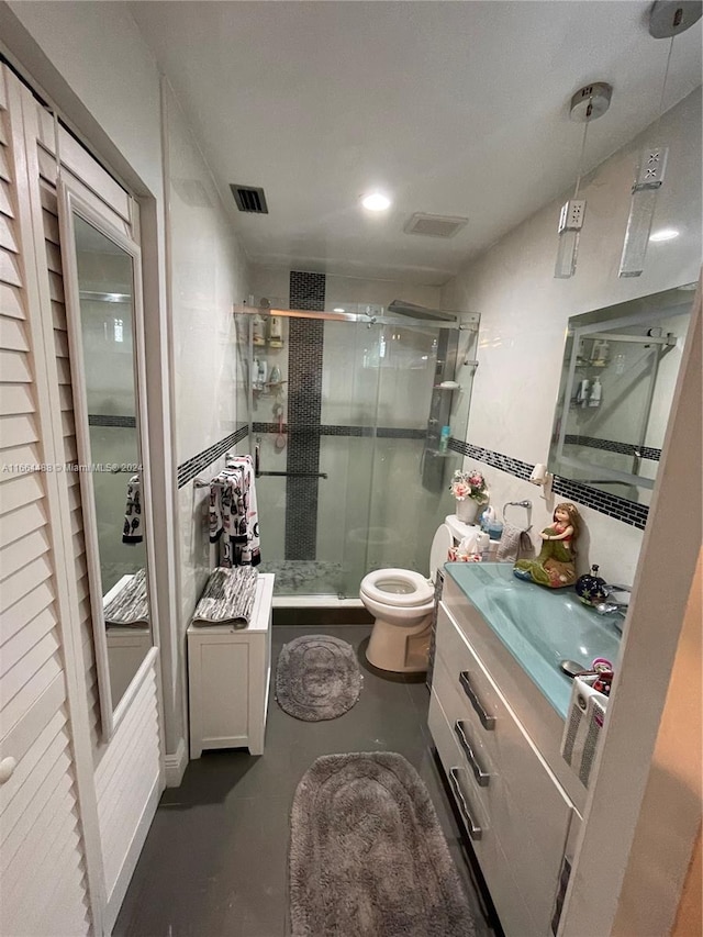 bathroom featuring concrete flooring, vanity, a shower with shower door, and toilet