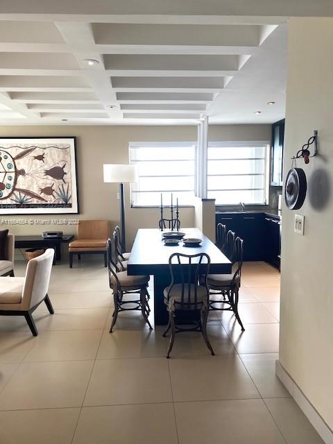 dining room with light tile patterned flooring, sink, and beamed ceiling