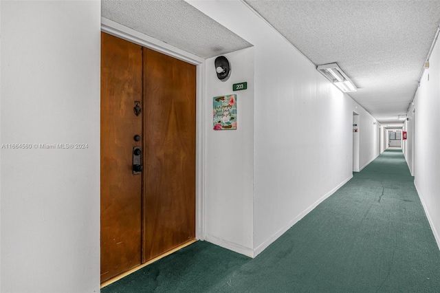 hall with dark colored carpet and a textured ceiling