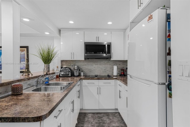 kitchen with white cabinetry, kitchen peninsula, black cooktop, white fridge, and sink